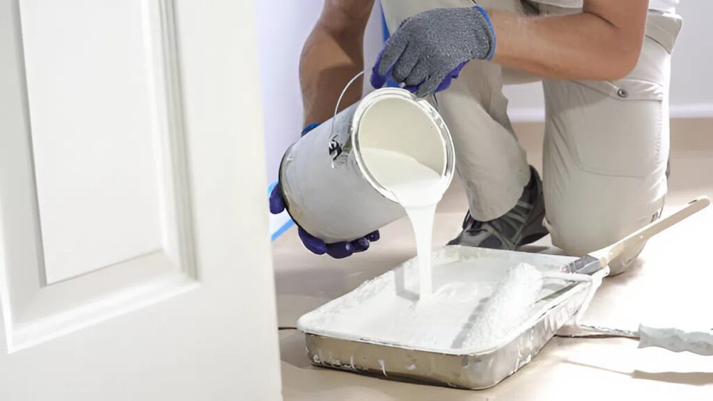 Professional interior painter in Grants Pass, OR, pouring white paint into a tray, preparing for a commercial wall project