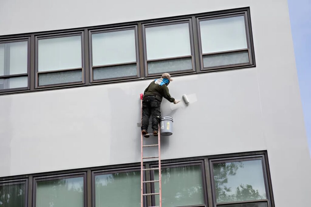 Fresh paint application to a building façade by a painter in Ashland, OR